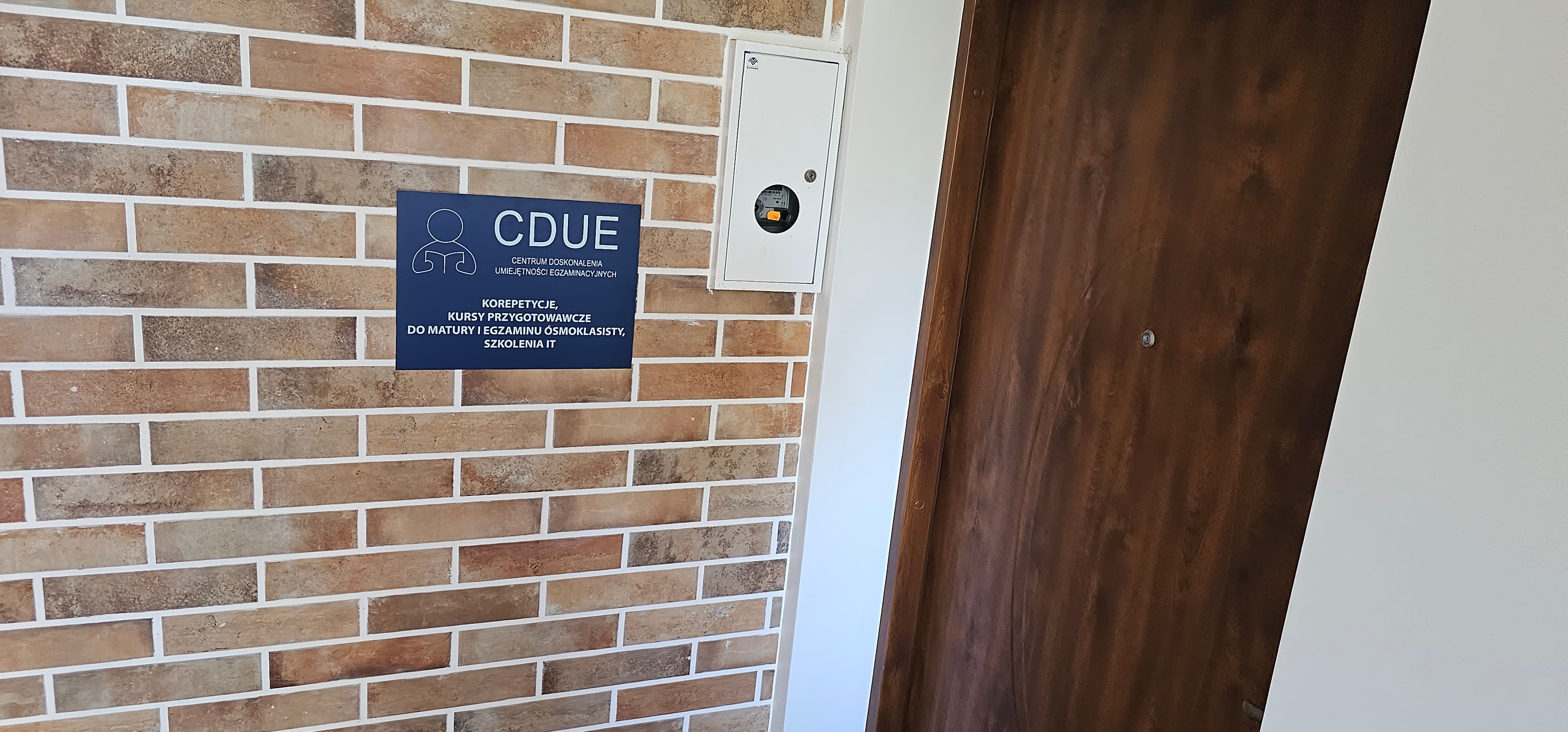 Wejście do placówki CDUE w Bydgoszczy z tablicą o korepetycjach, kursach i szkoleniach IT